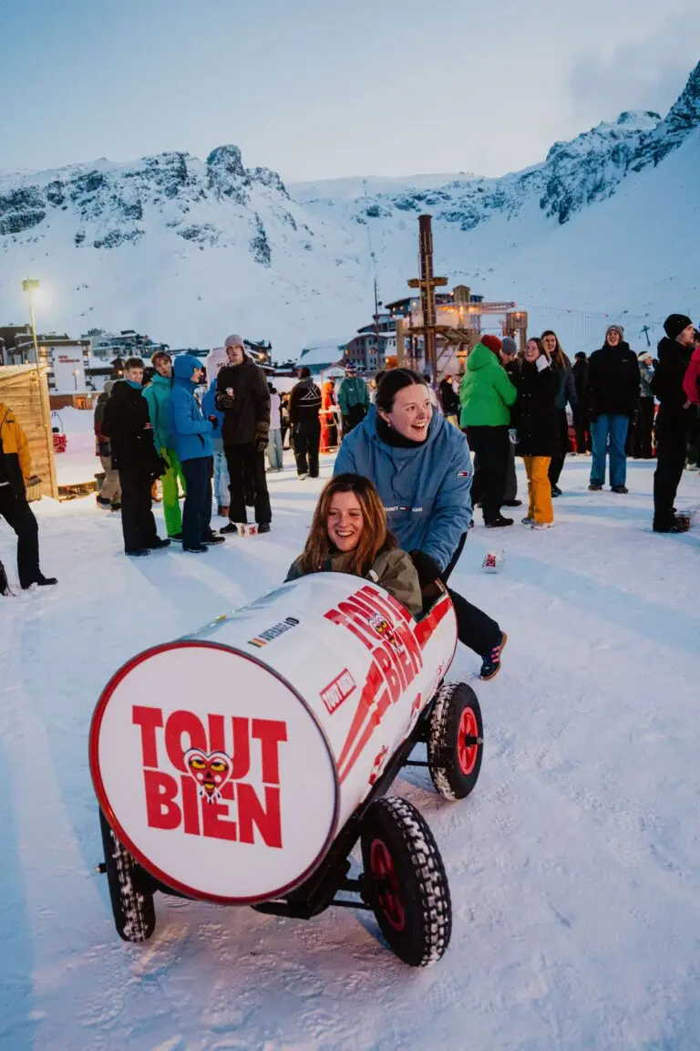 two women laughing in a barrel car at a snowy mountain event