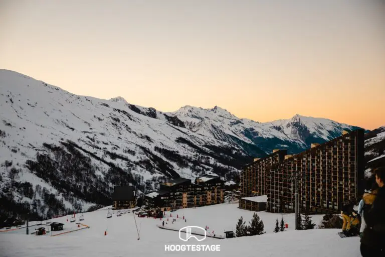 snowy mountain village at sunset with ski slopes